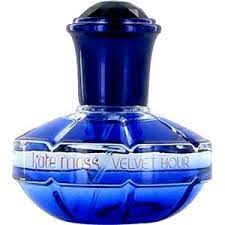A blue glass bottle of Kate Moss Velvet Hour 100ml Eau de Toilette, featuring a dark blue cap and silver text on the front, this elegant fragrance by Kate Moss for women embodies a mysterious and sophisticated allure.