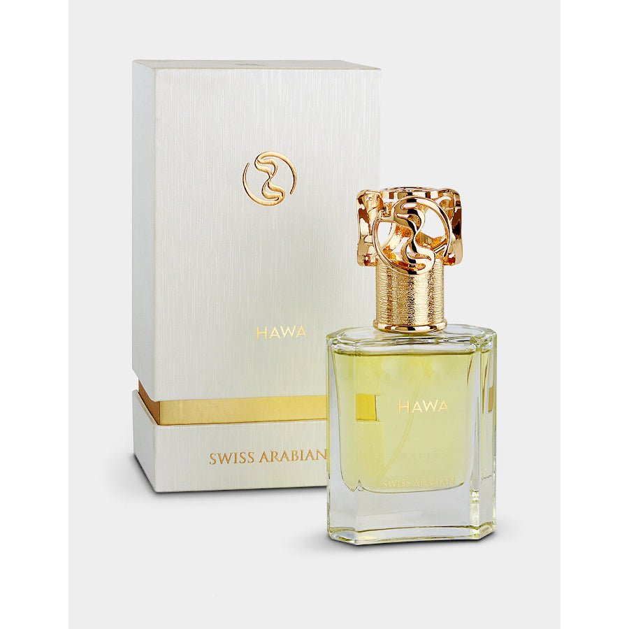 A gold-capped bottle of Swiss Arabian Hawa Extrait De Parfum stands before a matching white and gold box, both featuring the Swiss Arabian brand name and evoking the luxurious amber floral fragrance within.